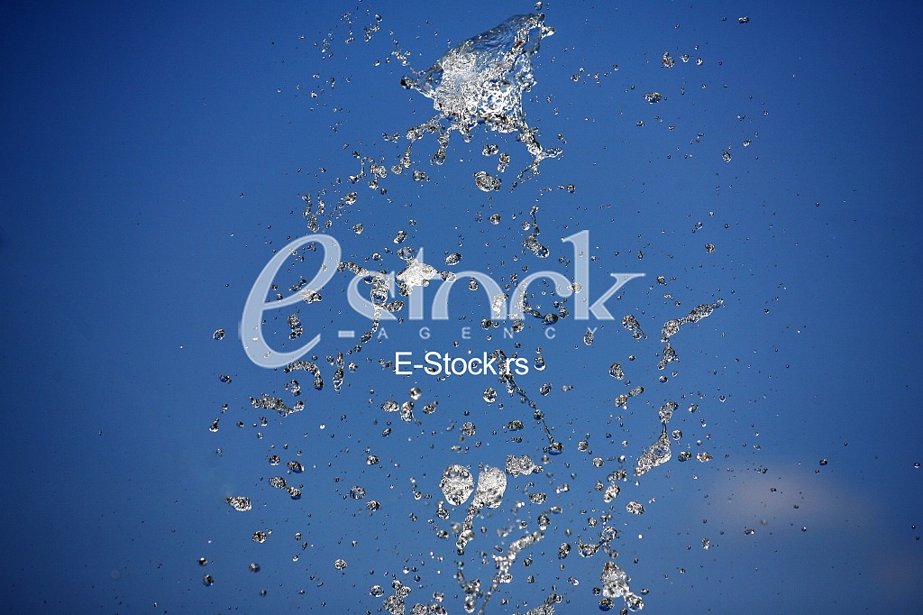 Fountain drops of pure brilliant water against a blue clear sky