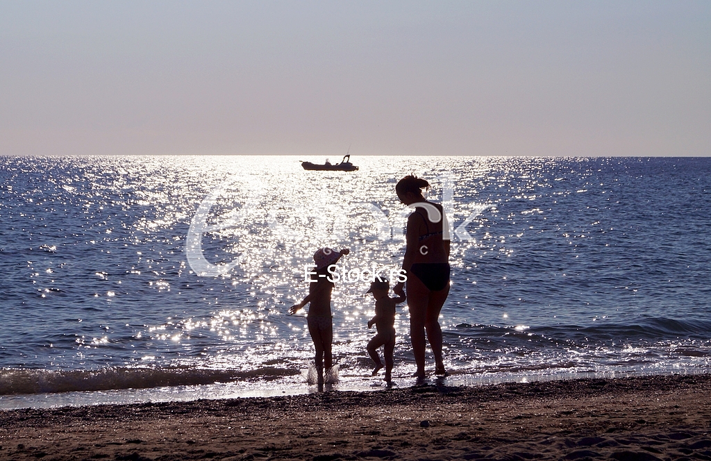 woman and kids dancing at the beach