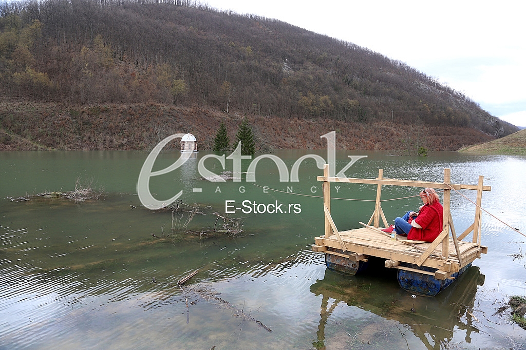 Woman looking the flooding Monastery Valjevska Gracanica in lake