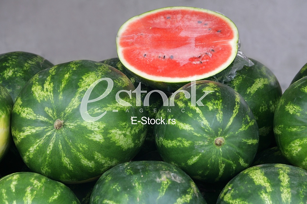 Many big sweet green watermelons and one cut watermelon background on the street market