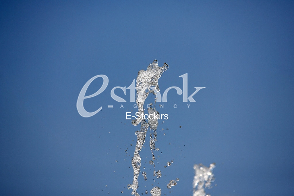 Fountain drops of pure brilliant water against a blue clear sky