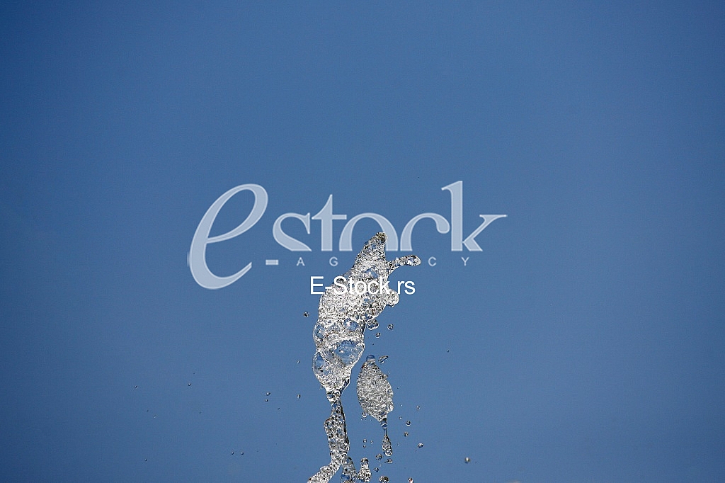 Fountain drops of pure brilliant water against a blue clear sky