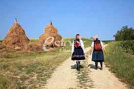 Summer mountain village outskirts with haystacks, stack of hay, two womans
