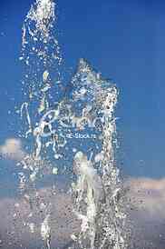 Fountain drops of pure brilliant water against a blue clear sky