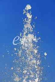 Fountain drops of pure brilliant water against a blue clear sky